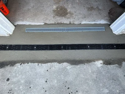 Channel drain grate set into a concrete driveway apron